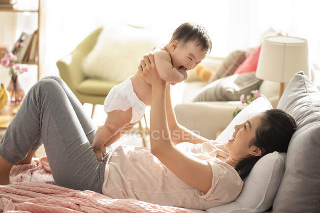 Мать и ребенок играют и смеются на диване — стоковое фото
