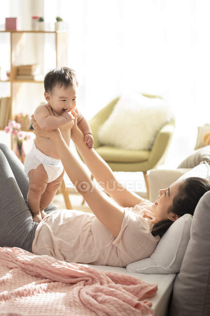 Mãe e bebê brincando e rindo no sofá — Fotografia de Stock