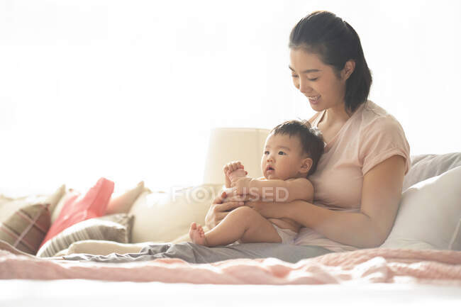 Mom holding baby while sitting on couch — Stock Photo