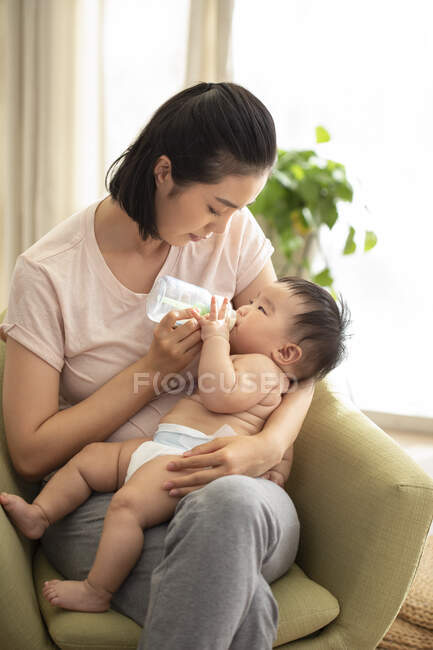 Jovem mãe alimentando seu bebê de mamadeira — Fotografia de Stock