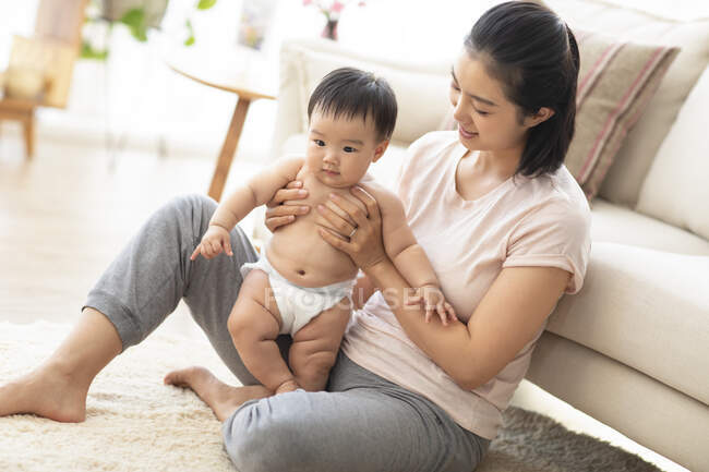 Mamma che tiene il bambino sul pavimento in soggiorno — Foto stock
