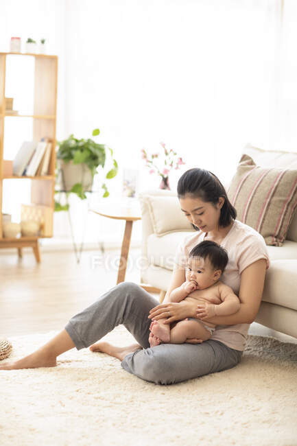 Mãe segurando bebê no chão na sala de estar — Fotografia de Stock