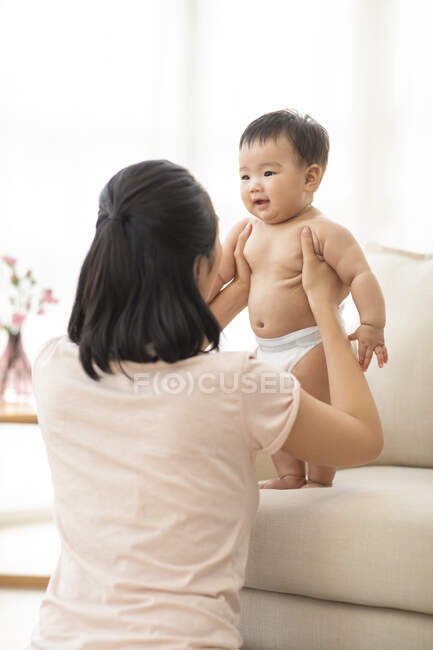 Jeune mère jouer avec bébé sur canapé — Photo de stock