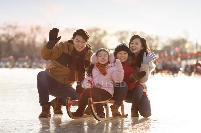 Happy young Chinese family sledding outdoors — Stock Photo