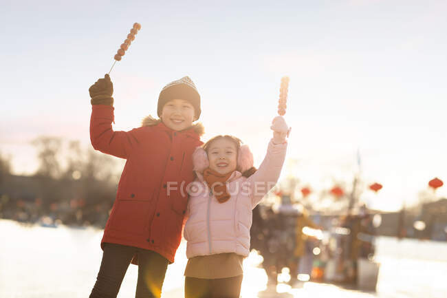 Happy Chinese sibling eating candied haws outdoors — Stock Photo