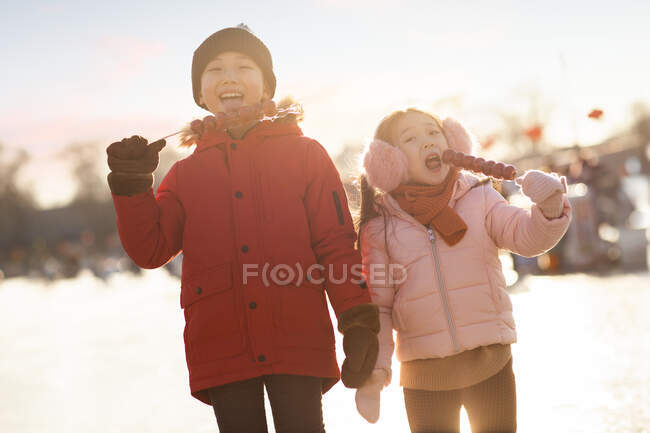 Счастливые китайские братья и сёстры едят леденцы на открытом воздухе — стоковое фото