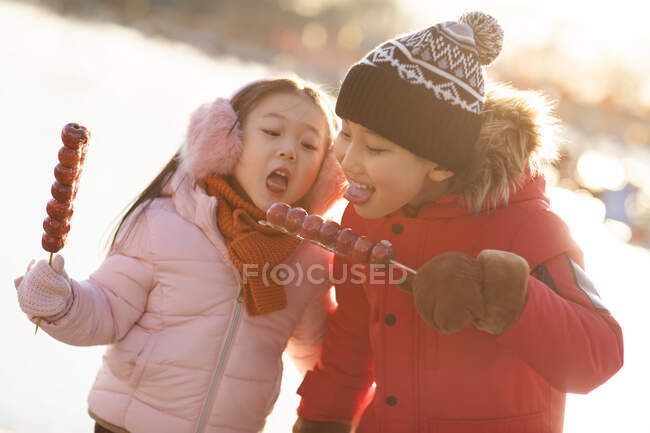 Happy Chinese sibling eating candied haws outdoors — Stock Photo