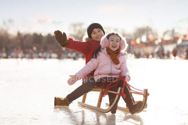 Glückliche chinesische Geschwister beim Rodeln im Freien — Stockfoto