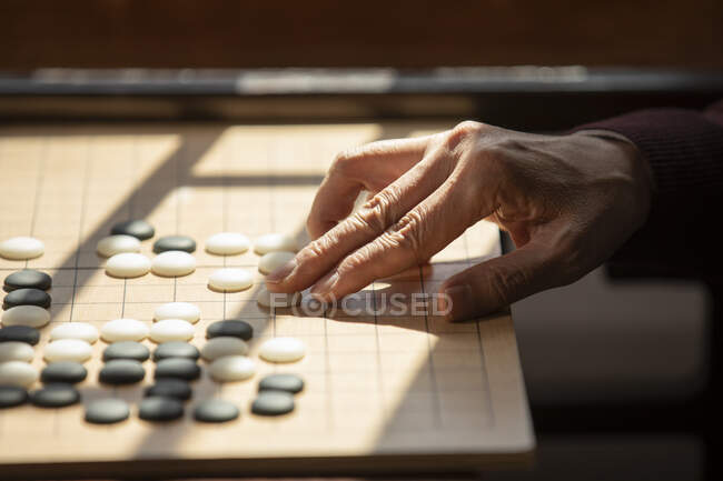 Cropped shot of senior man hand playing game of go — Stock Photo