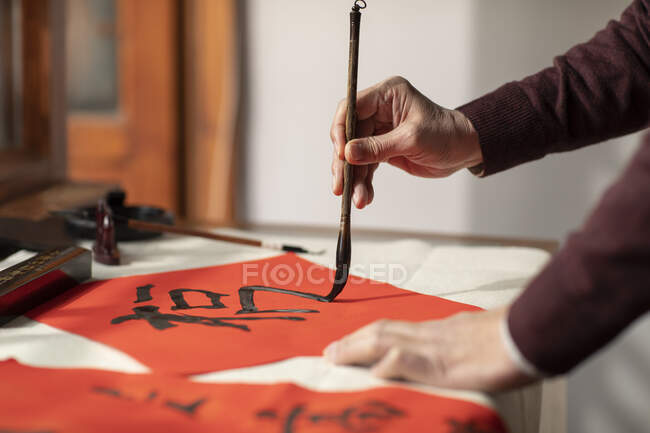 Обрізаний знімок рук старшого чоловіка, що пишуть каліграфію на гніздах — стокове фото