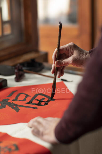 Cropped shot of senior man hands writing calligraphy on couplets — Stock Photo