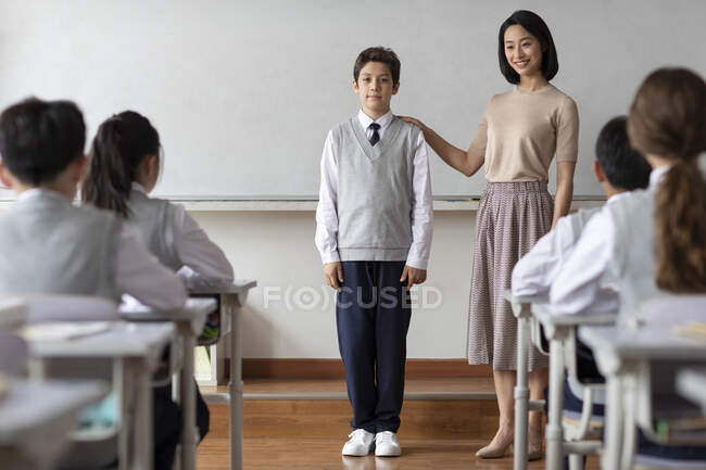 Joven profesor chino presentando a un nuevo compañero de clase en el aula - foto de stock