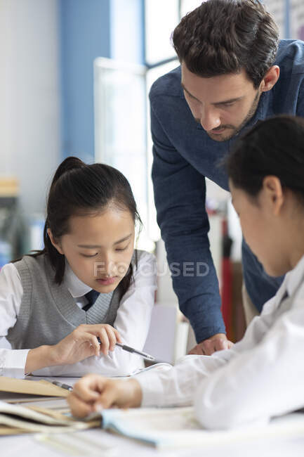 Young teacher helping students in classroom — Stock Photo