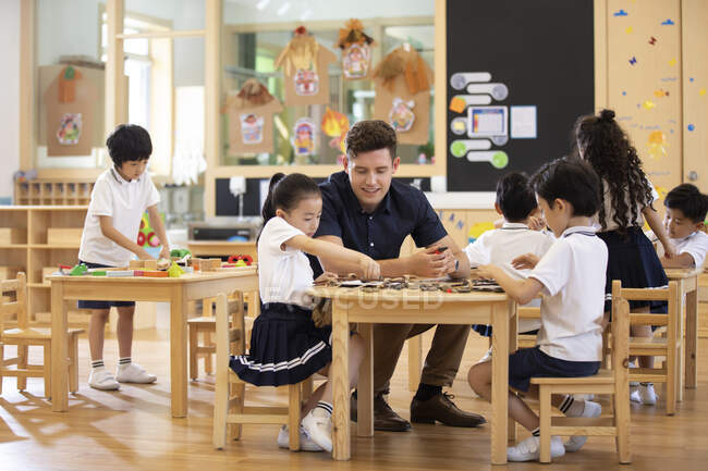 Ausländische Lehrer und Kinder spielen im Klassenzimmer — Stockfoto