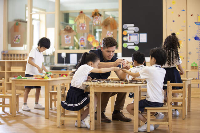 Ausländische Lehrer und Kinder spielen im Klassenzimmer — Stockfoto