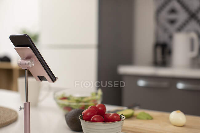 Salad ingredients on table and smartphone on metal stand — Stock Photo