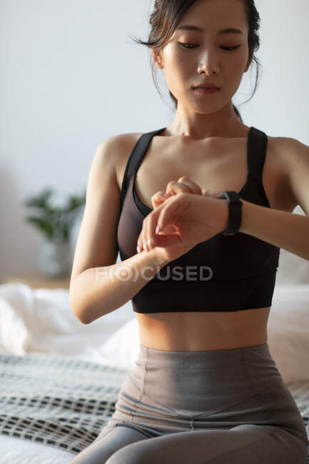 Молодая китаянка смотрит на умные часы после тренировки — стоковое фото
