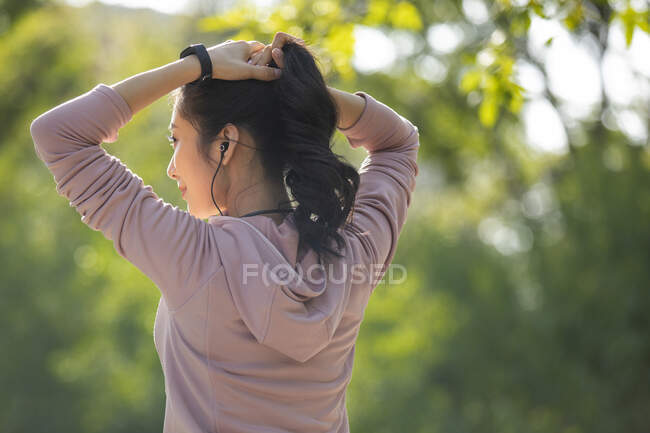 Задний вид женщины в спортивной одежде, завязывающей волосы — стоковое фото