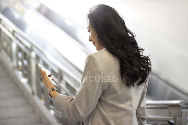Young chinese woman using smartphone in airport — Stock Photo