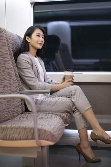 Woman sitting in high-speed train with coffee cup — Stock Photo