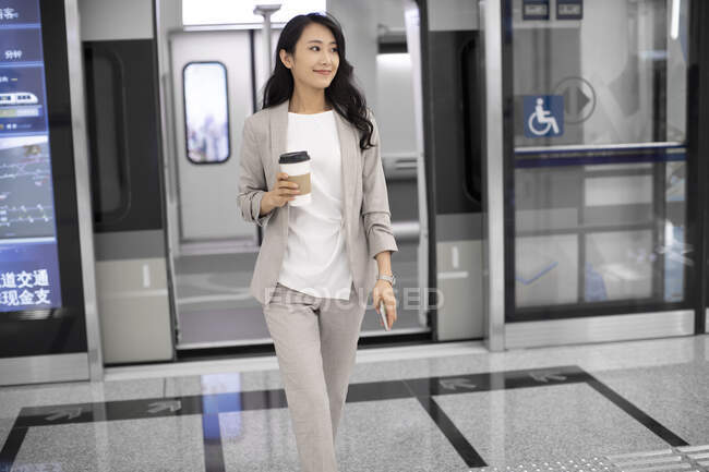 Woman walking out of subway with coffee — Stock Photo