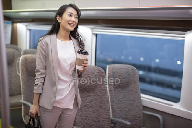 Woman standing in high-speed train with coffee cup — Stock Photo