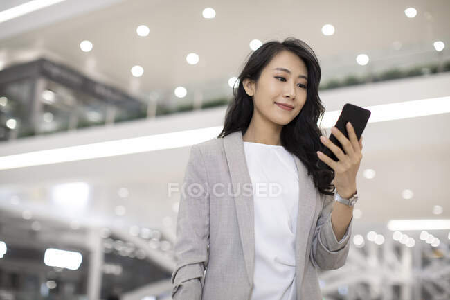 Jeune femme chinoise utilisant un smartphone à l'aéroport — Photo de stock