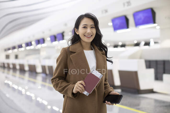 Happy woman with passport and airplane ticket in airport — Stock Photo
