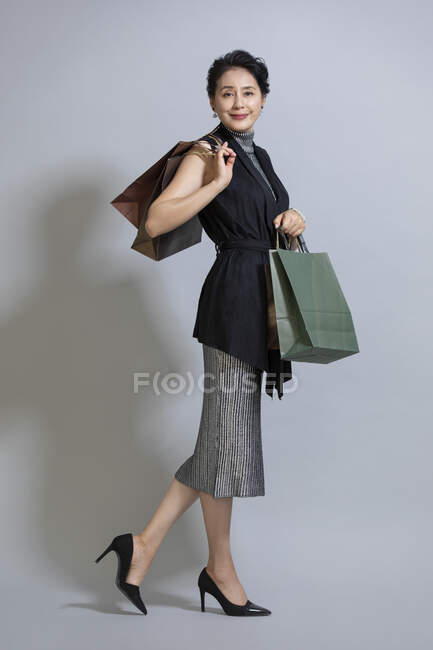 Зріла китайська жінка позує з сумками — стокове фото