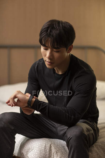Young chinese man looking at wrist watch — Stock Photo