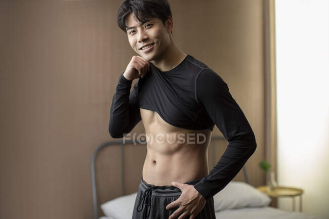 Young chinese man smiling and showing abs — Stock Photo