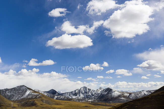 Vista panorâmica do vale e montanhas rochosas sob céu azul nublado no Tibete, China — Fotografia de Stock