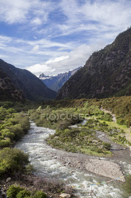 Rocky river with mountains and cloudy sky, Tibet, China — Stock Photo