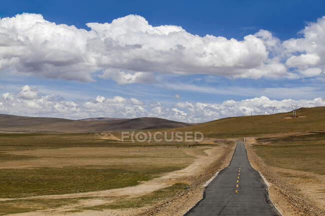 Вид на дорогу с шипами и облачным небом в Тибете, Китай — стоковое фото