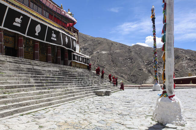Monjes en las escaleras de entrada del monasterio de Drepung en el Tíbet, China - foto de stock