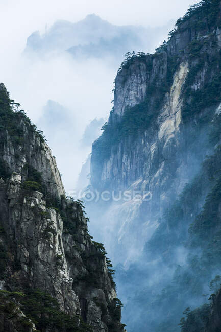 Rochas com árvores e nuvens baixas, Huangshan, China — Fotografia de Stock