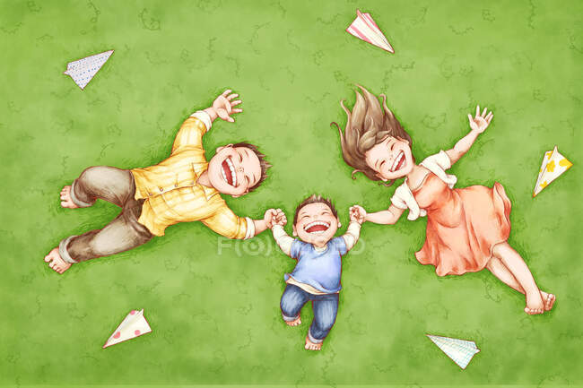 Молодая семья лежит на траве с бумажными самолетами — стоковое фото