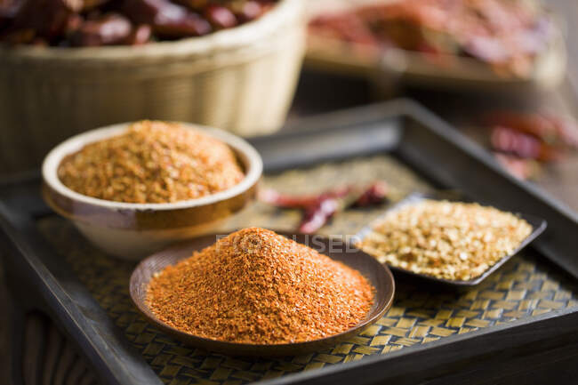 Red chili powder in bowl with bowls of seeds — Stock Photo