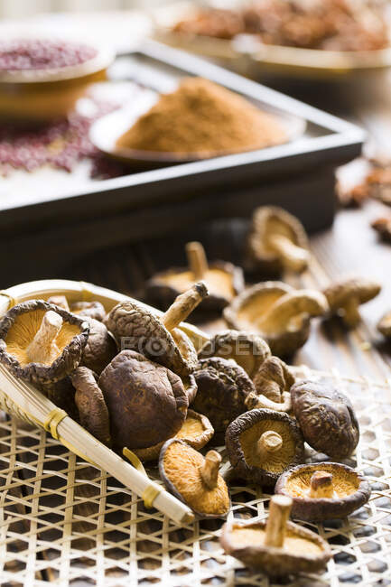 Getrocknete Shiitake-Pilze in Holzschaufel und auf dem Tisch — Stockfoto
