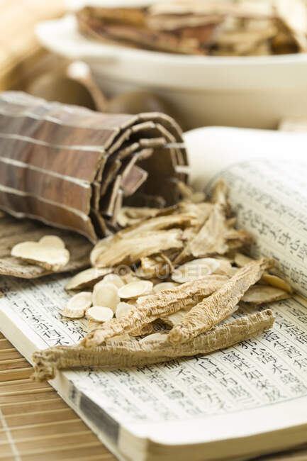 Medicina herbal china, hierbas secas en libro con jeroglíficos - foto de stock