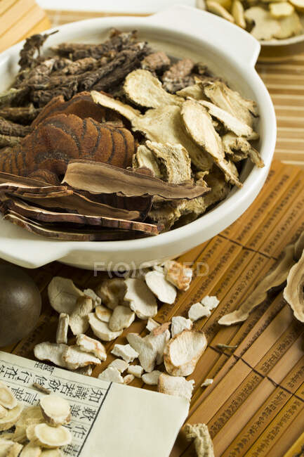 Chinesische Kräutermedizin, getrocknete Kräuter in Schale auf Bambuszetteln — Stockfoto