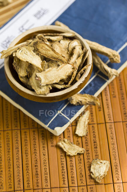 Dried codonopsis pilosula in bowl on books — Stock Photo