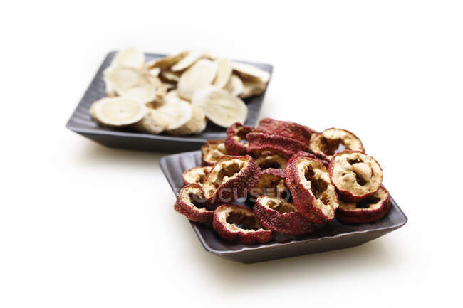 Medicina tradicional china, pimiento seco y rodajas de jengibre en platos - foto de stock