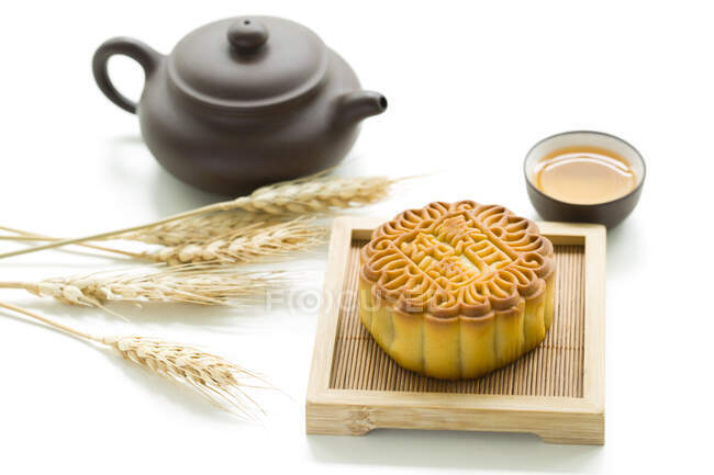 Mooncake and tea in cup and teapot with spikelets on white table — Stock Photo