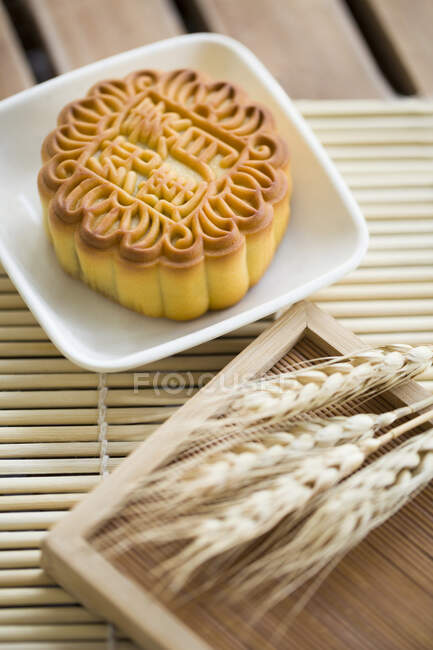 Mooncake in bowl with spikelets on table — Stock Photo