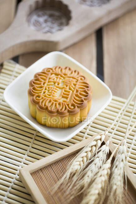 Mooncake in bowl with spikelets on table — Stock Photo