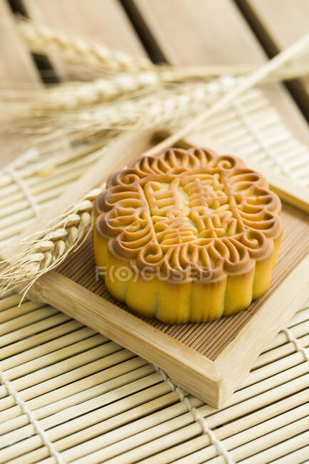 Mooncake on small wooden tray with spikelets — Stock Photo