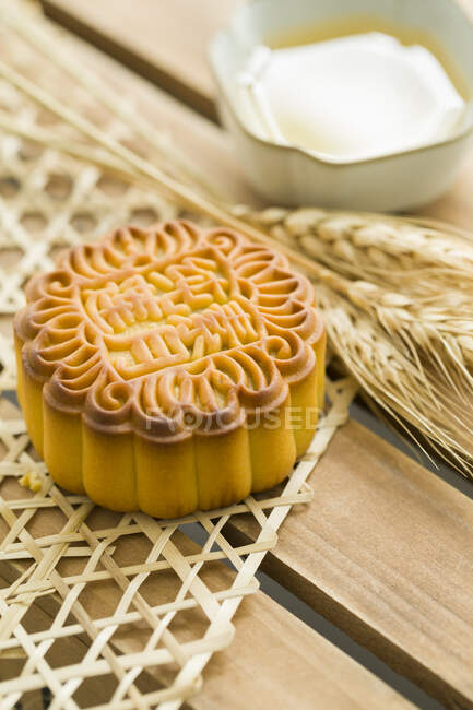 Pastel de luna chino tradicional con espiguillas en la mesa - foto de stock