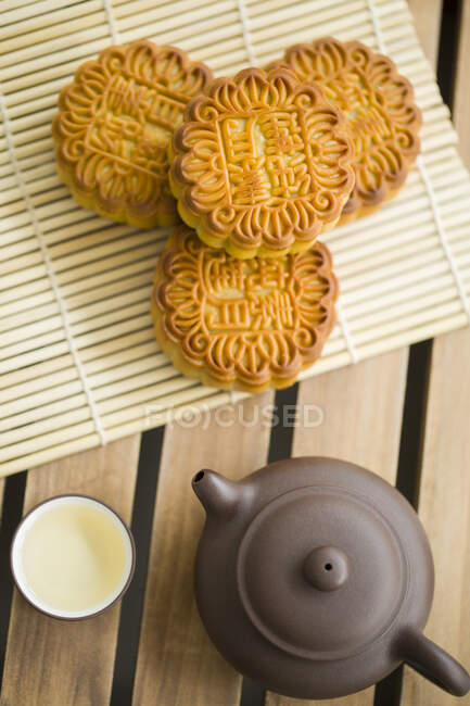 Bolos de lua em tapete de bambu e chá em bule e xícara — Fotografia de Stock