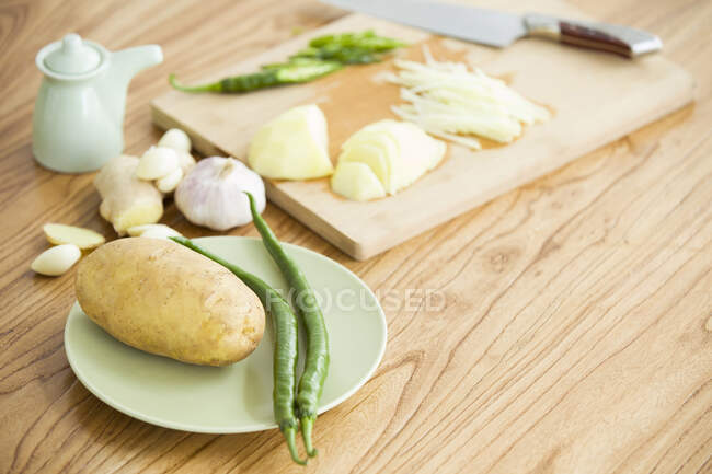 Pomme de terre râpée avec des piments verts, des ingrédients sur l'assiette et une planche à découper — Photo de stock